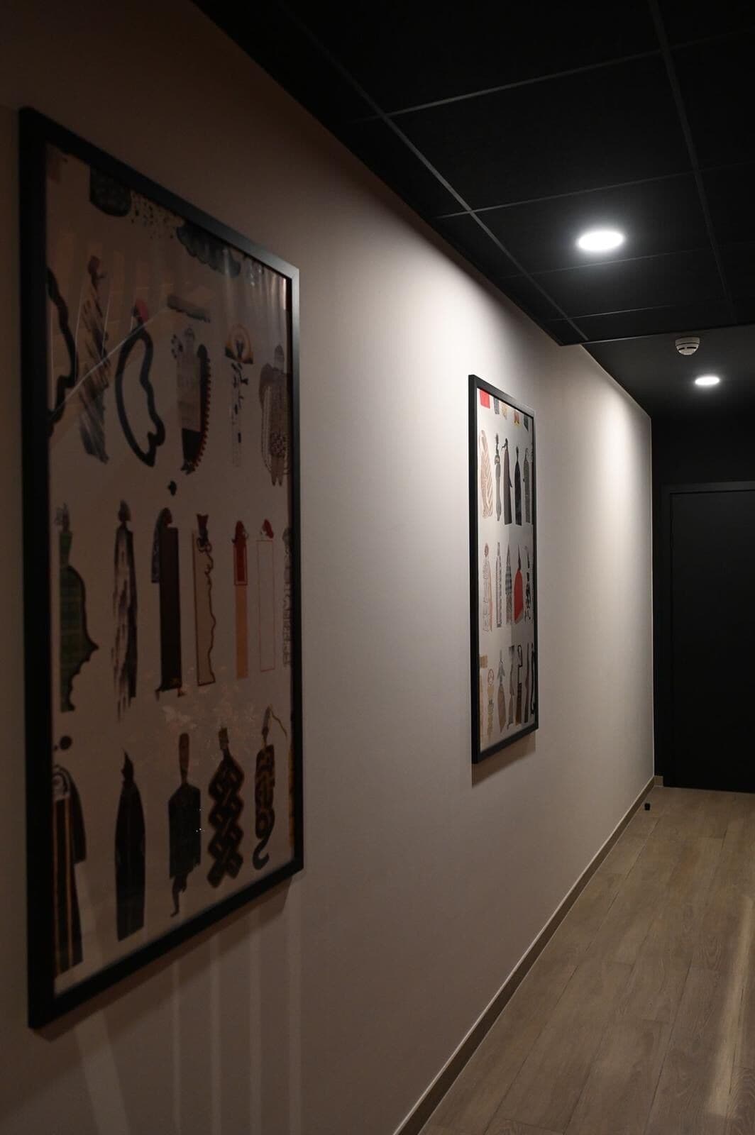 Un pasillo con dos obras de arte enmarcadas en la pared.
