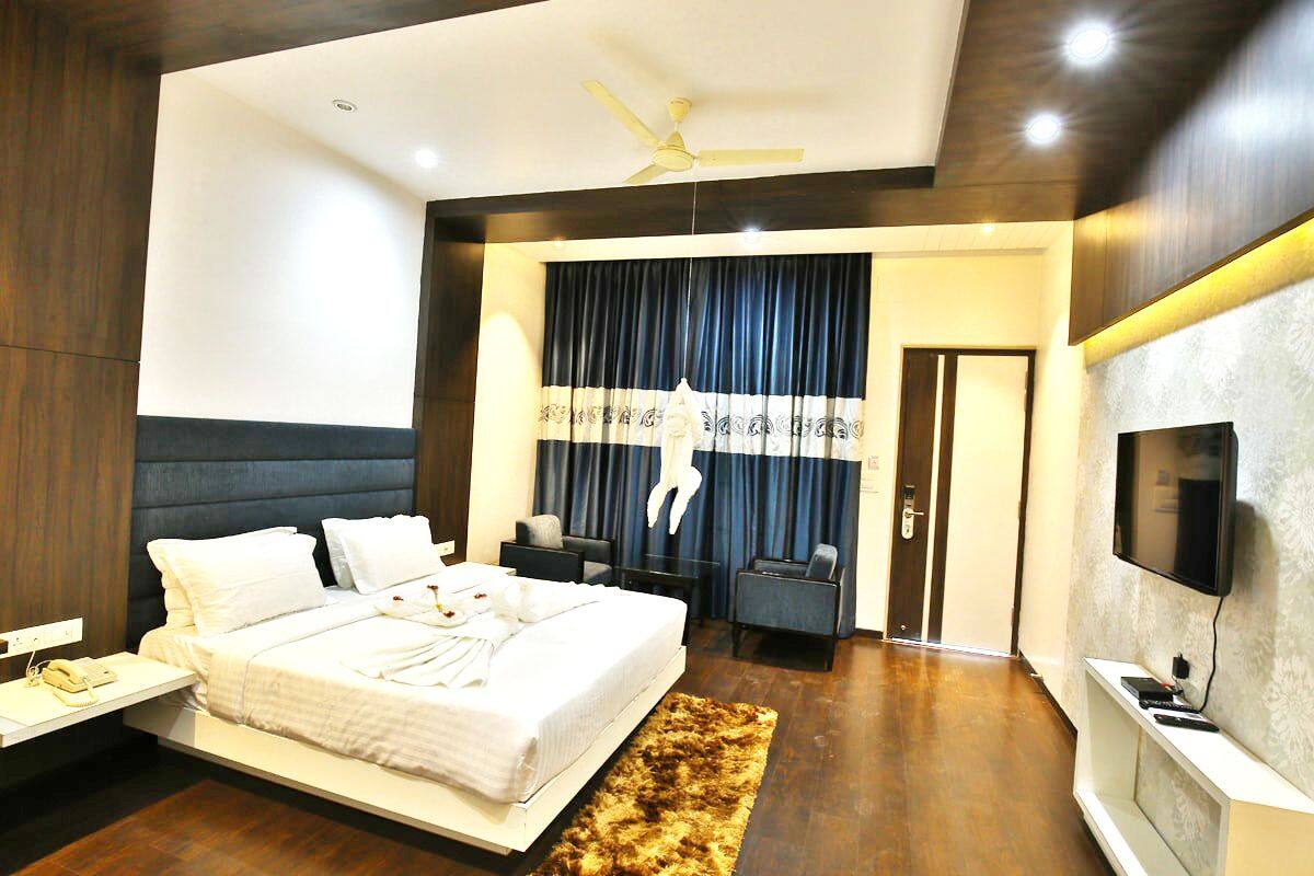 A modern hotel room with a large bed, a flat-screen TV, a desk with a telephone, and a ceiling fan.