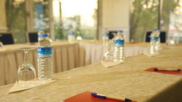 Una mesa servida con botellas de agua, vasos y un bloc de notas con un bolígrafo.
