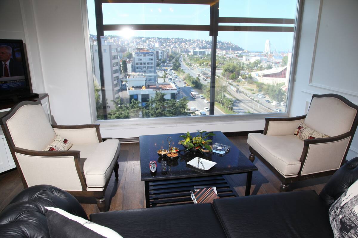 A living room with a large window, two armchairs, a coffee table, and a TV.