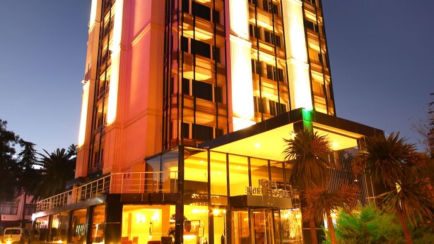 Un hotel de varios pisos con una entrada destacada y fachada de vidrio.