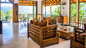 A spacious room with wooden furniture, large windows, and a view of greenery. - Aqua Dunhinda Villa & Nature Retreat (Kandy)
