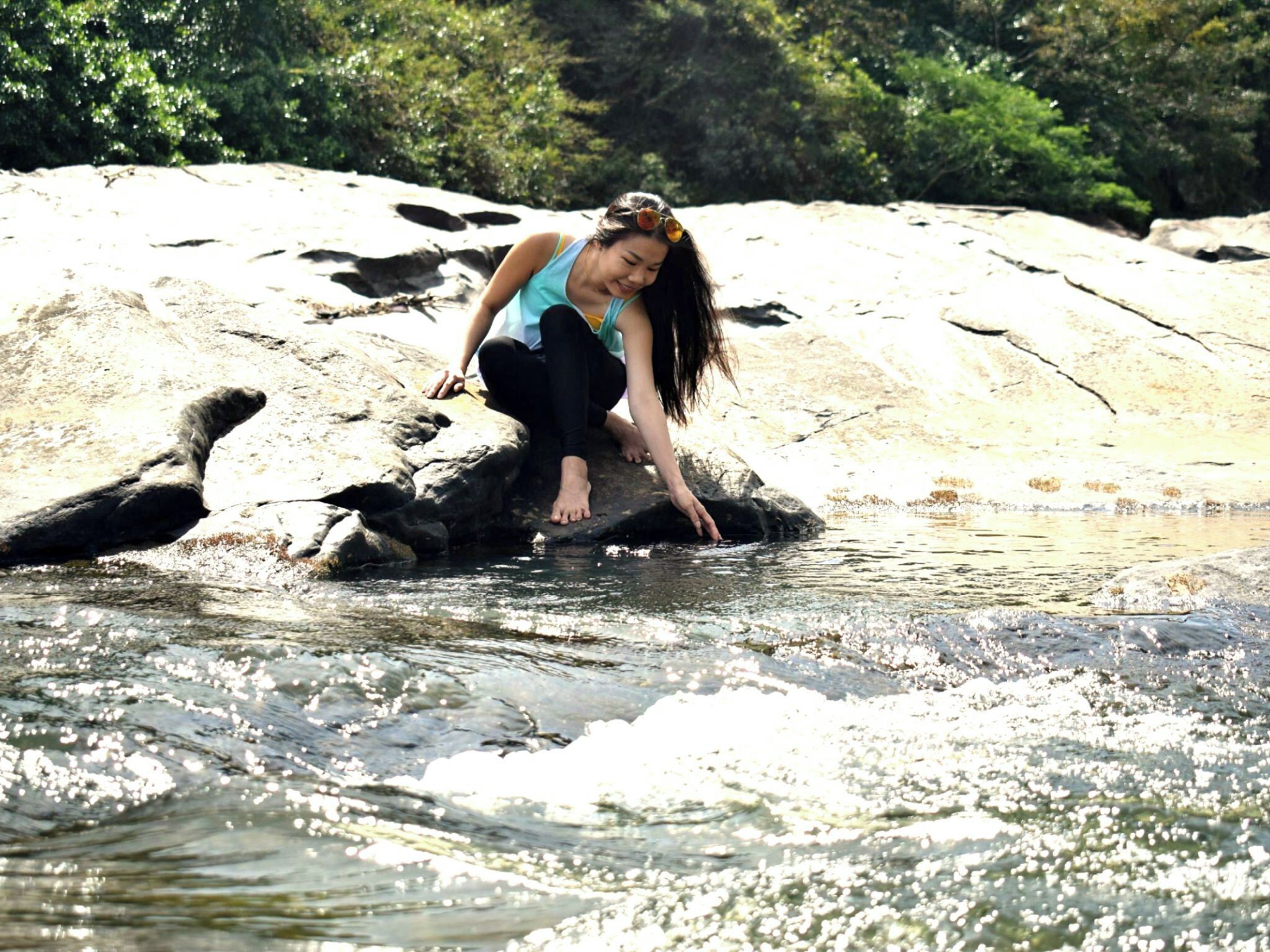 A person sitting on a rock by a flowing river.