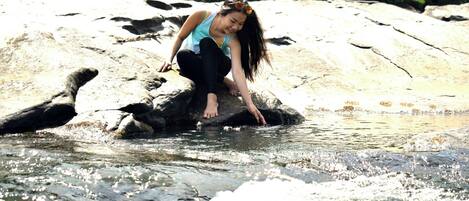 A person sitting on a rock by a flowing river.