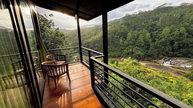 A balcony with wooden flooring and metal railings, overlooking a lush green forest and a river. - Aqua Dunhinda Villa & Nature Retreat (Kandy)