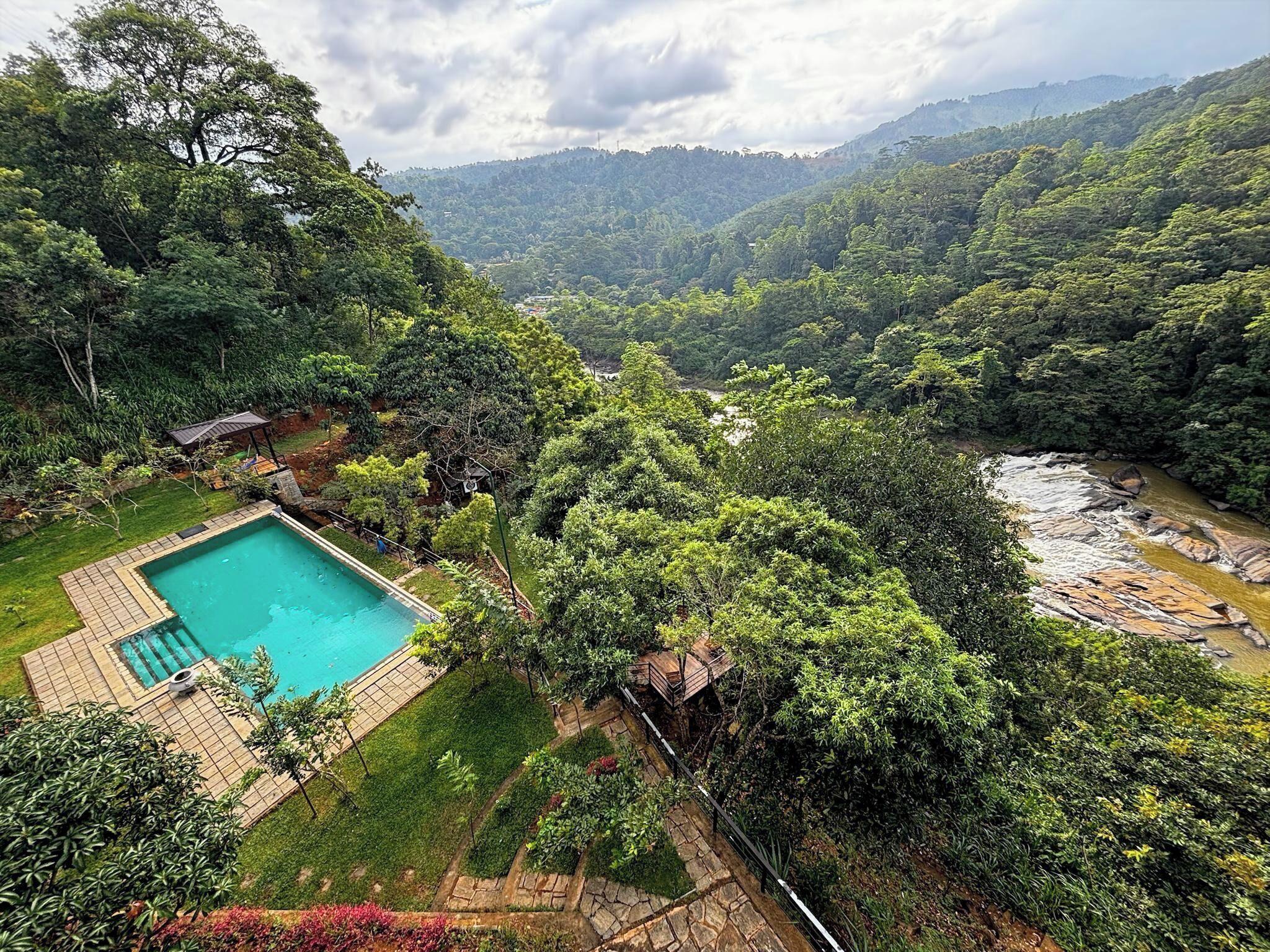 A pool surrounded by lush greenery and a river.