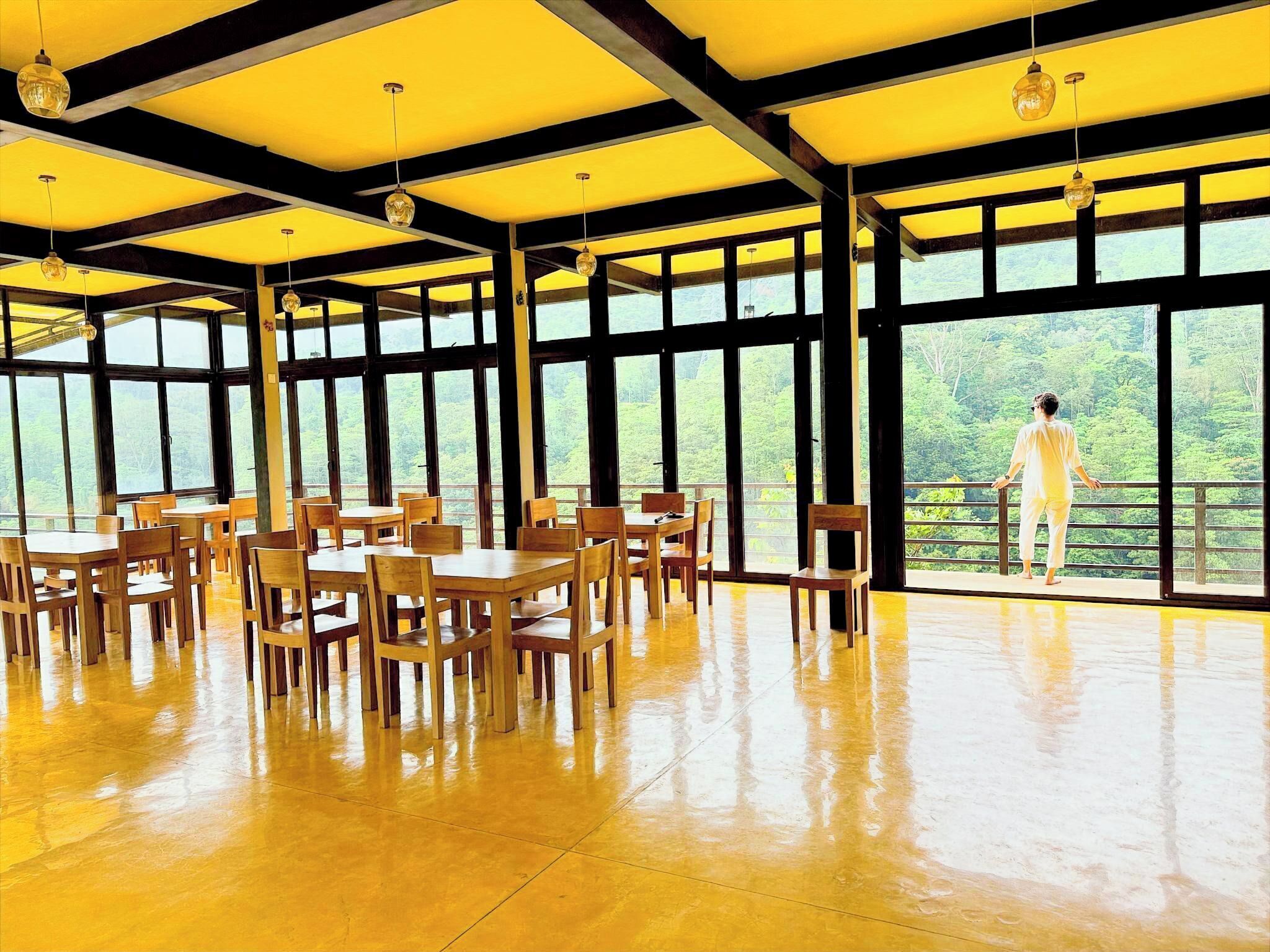 A spacious dining area with large windows and wooden tables and chairs.