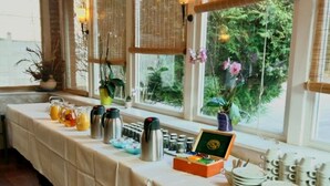 A long table with a white tablecloth, various food and drink containers, and a box of condiments.