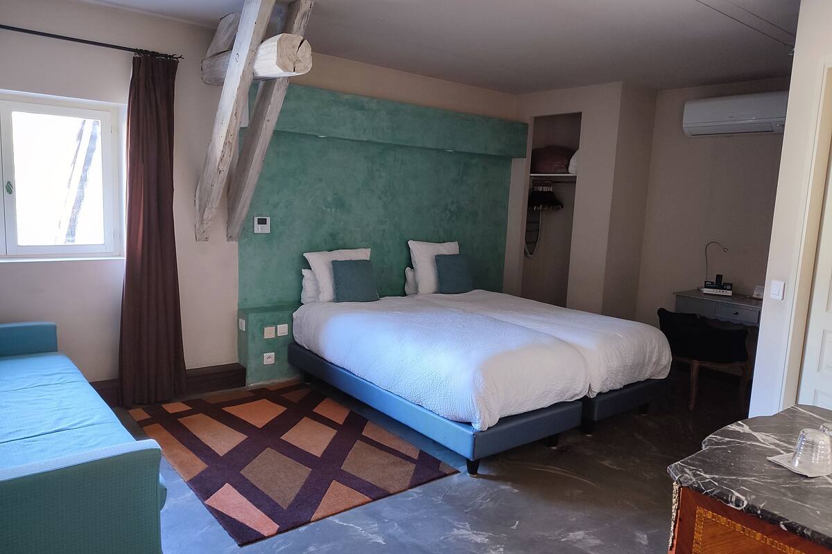 A bedroom with a bed, a desk, and an air conditioning unit.
