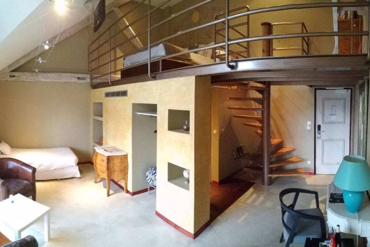 A room with a bunk bed, a desk, a chair, and a staircase.
