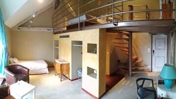 A room with a bunk bed, a desk, a chair, and a staircase.