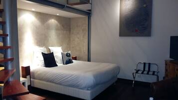 A modern bedroom with a bed, a painting of a fingerprint, a chair, and a water bottle on a table.