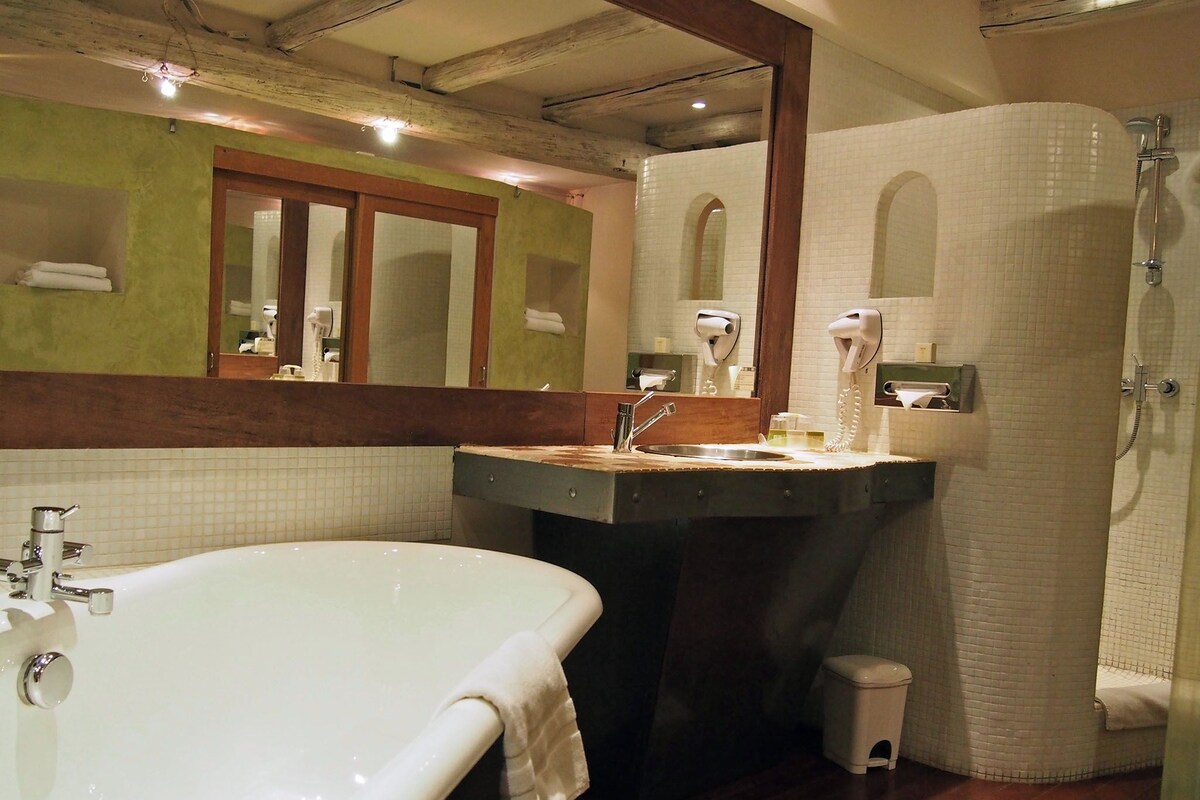 A bathroom with a large bathtub, a sink with a mirror, and a shower area.