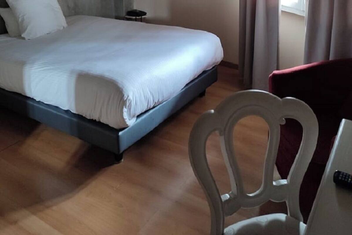 A bedroom with a bed, a chair, a desk, and a window with curtains.