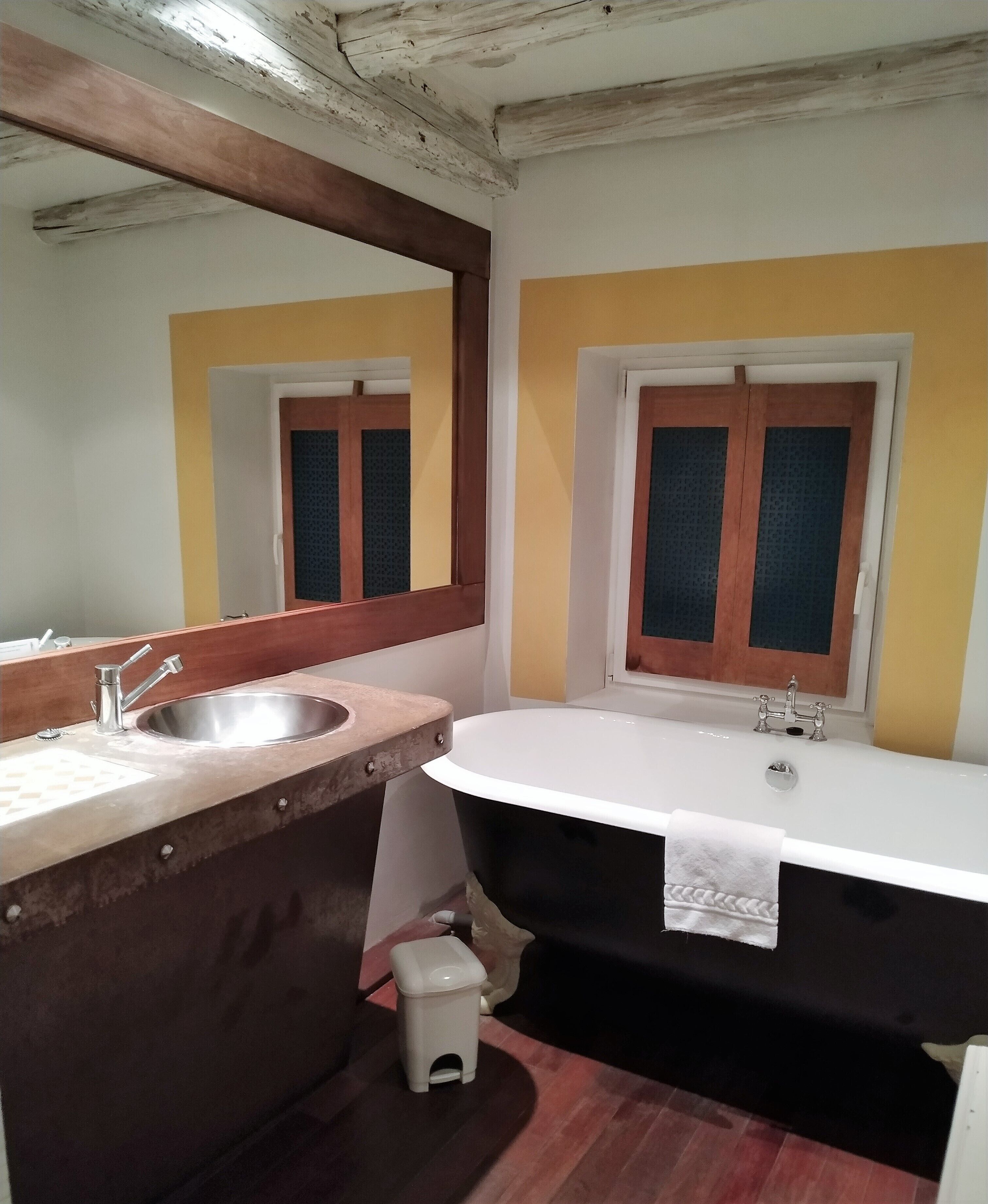 A bathroom with a sink, mirror, and bathtub.