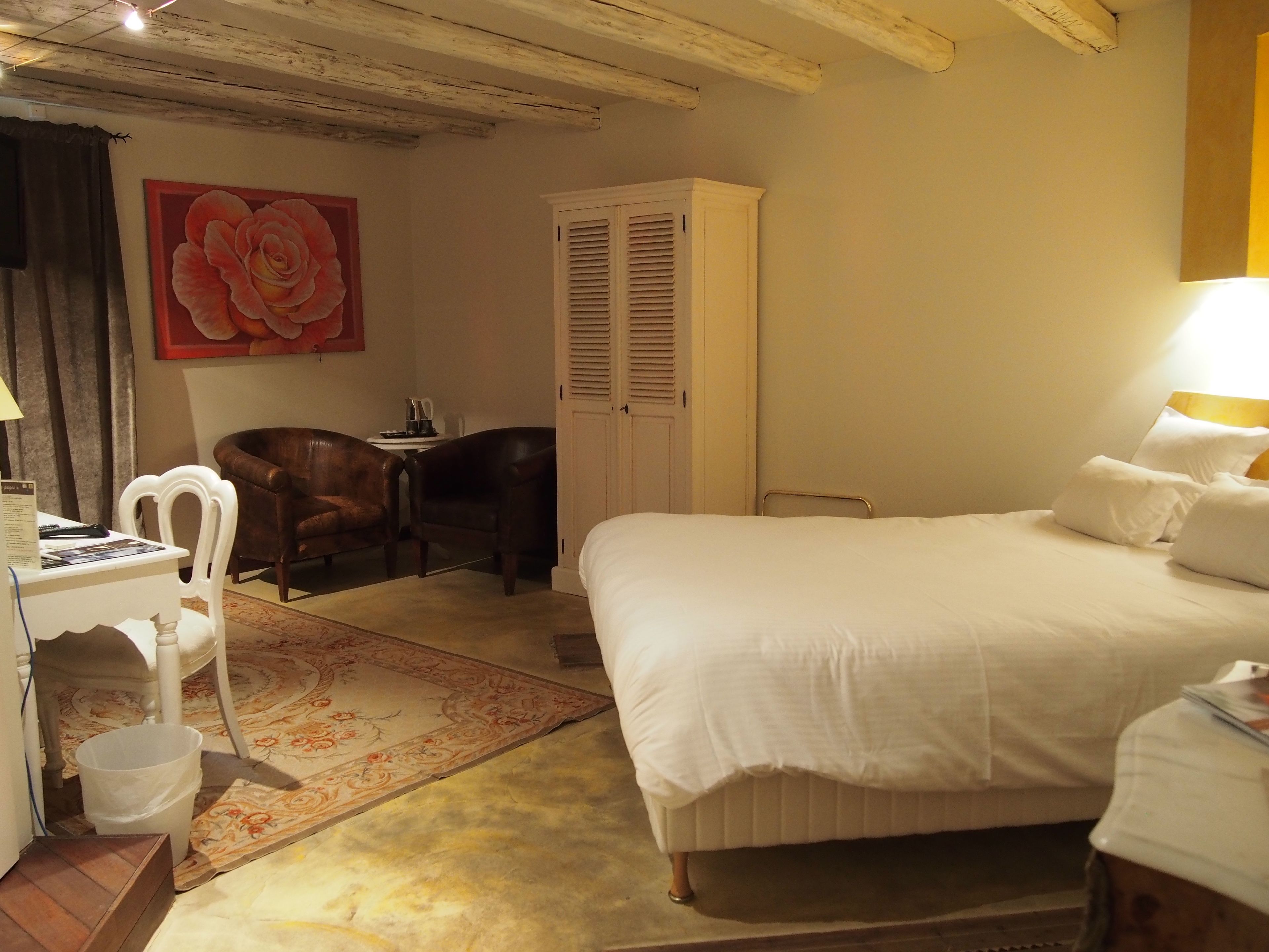 Une chambre d’hôtel avec un grand lit, un bureau avec une chaise, une armoire et un tableau au mur.