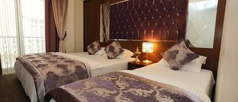 A hotel room with two beds, a large mirror, and a decorative headboard.