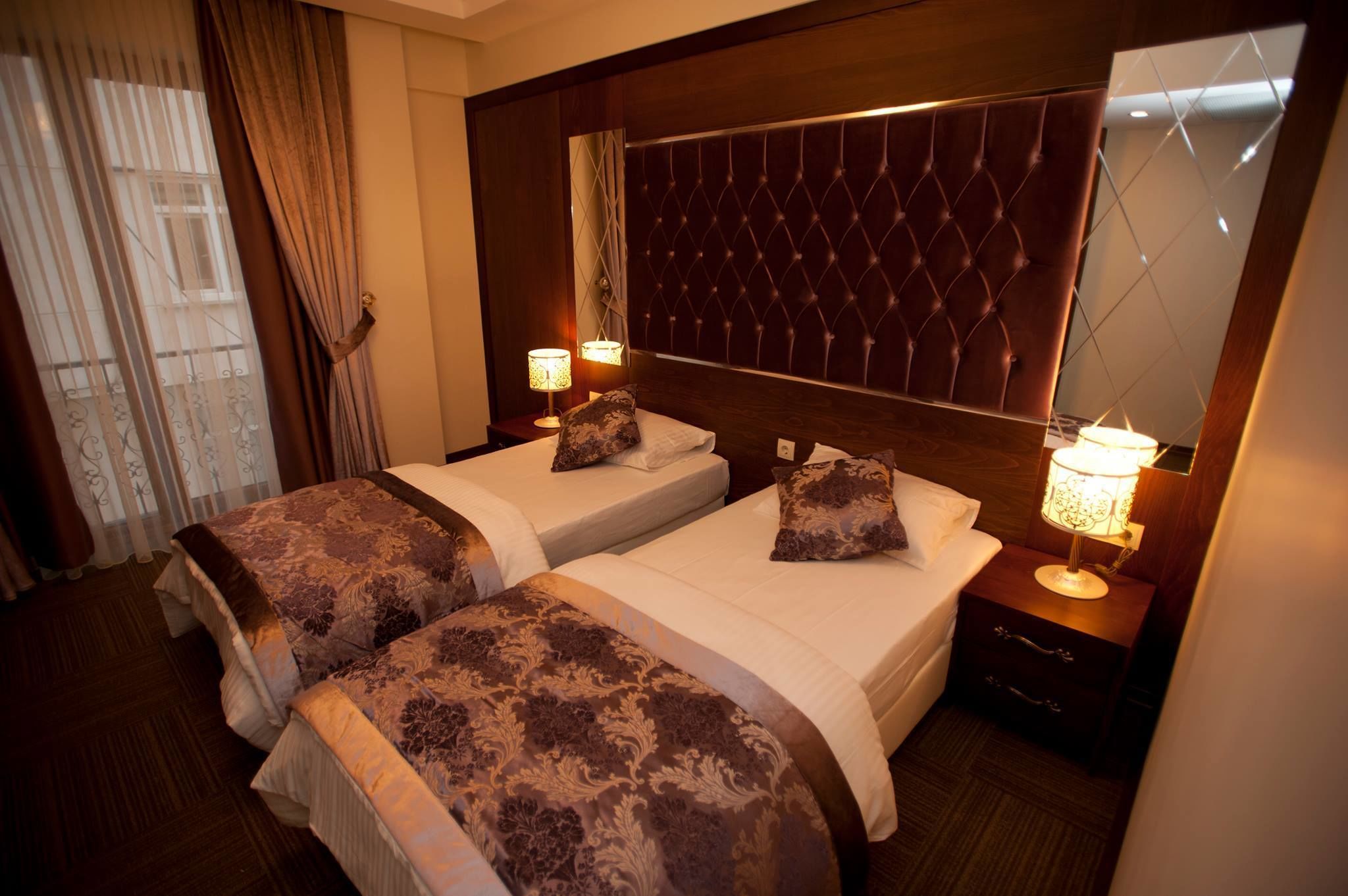 A hotel room with two beds, a large mirror, and bedside lamps.
