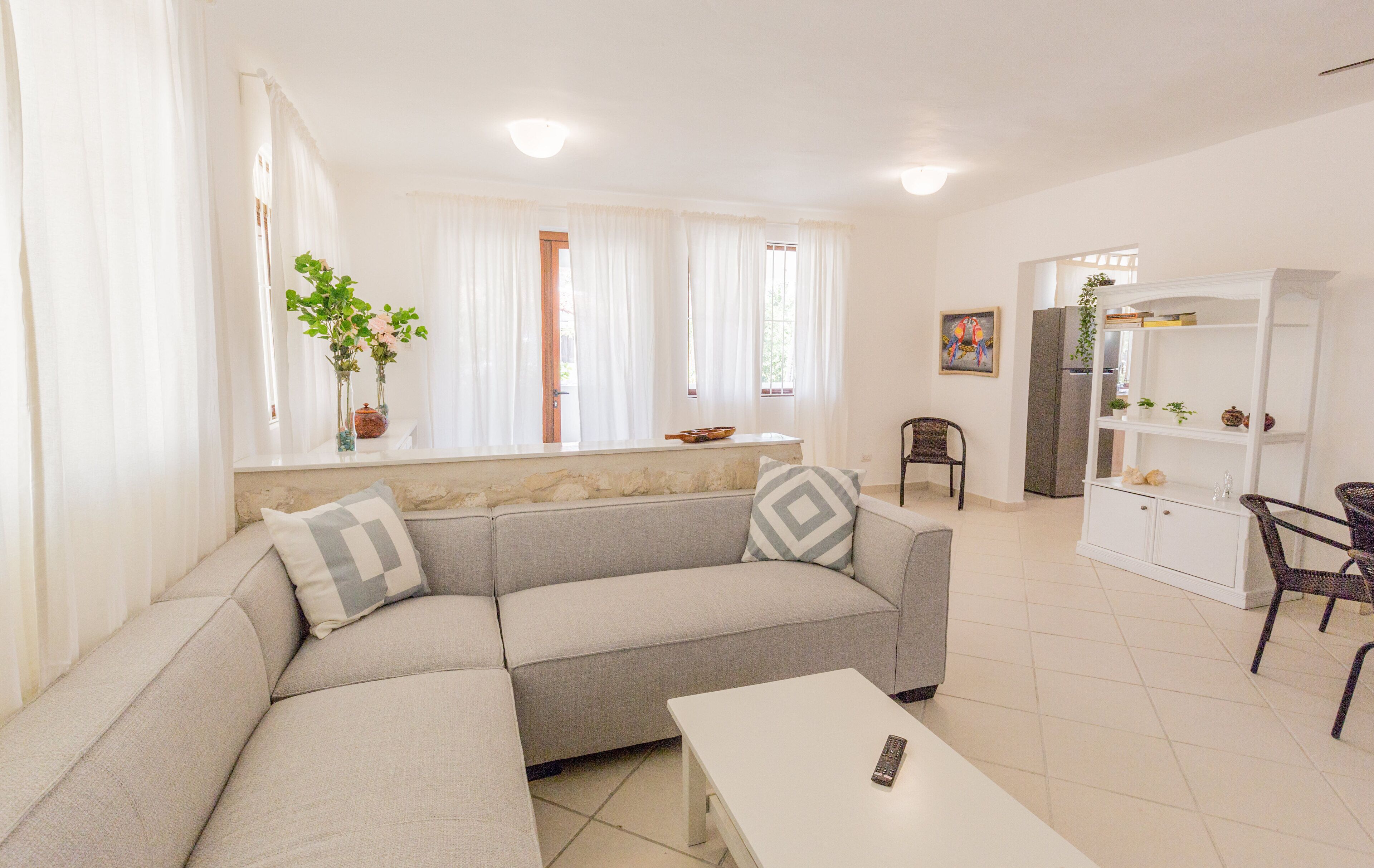 Un saló modern amb un sofà, una taula de centre i una zona menjador amb cadires i un moble d'armari.