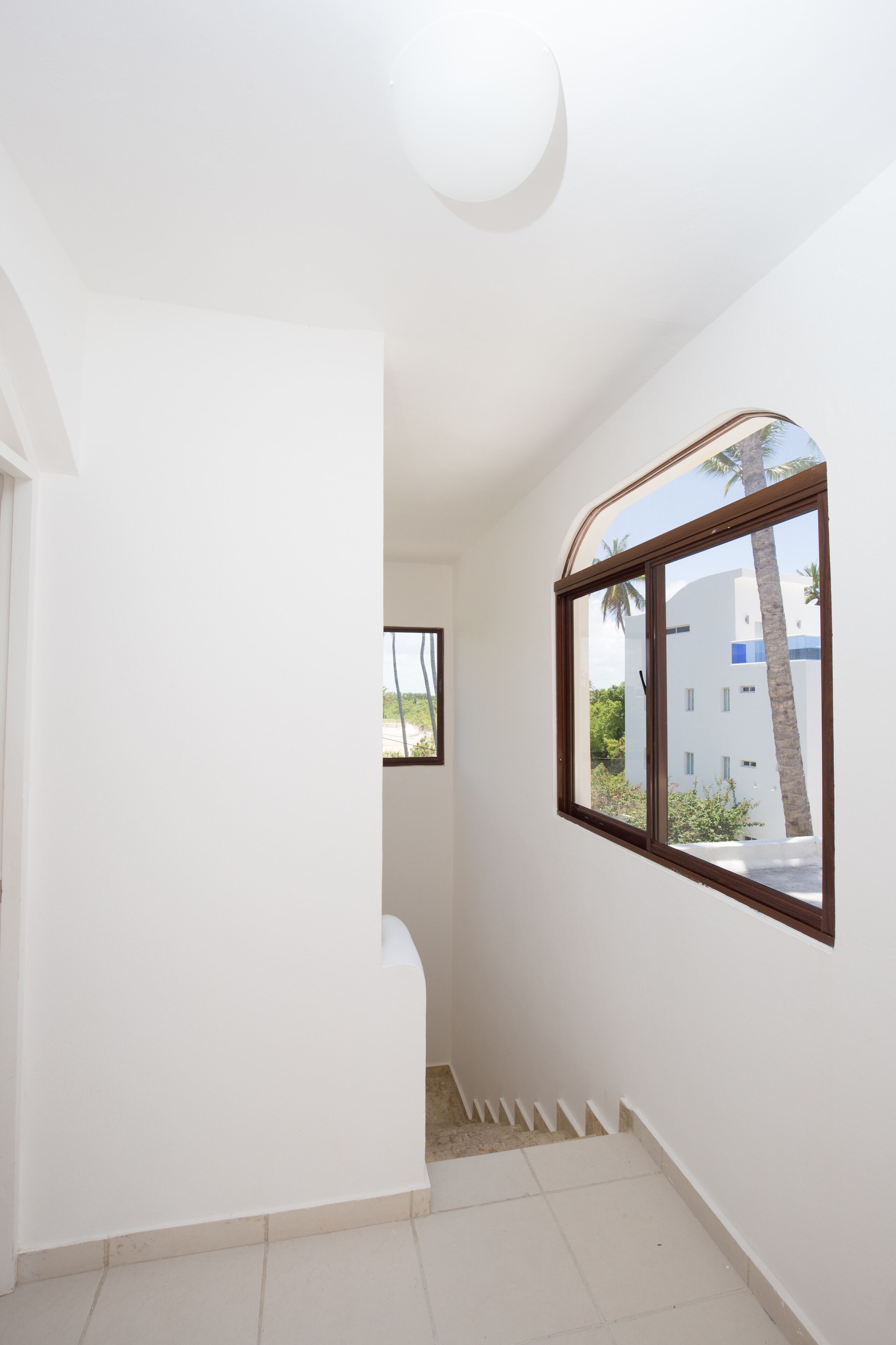 Un interno pulito e luminoso, con una finestra che si affaccia su un edificio e palme.