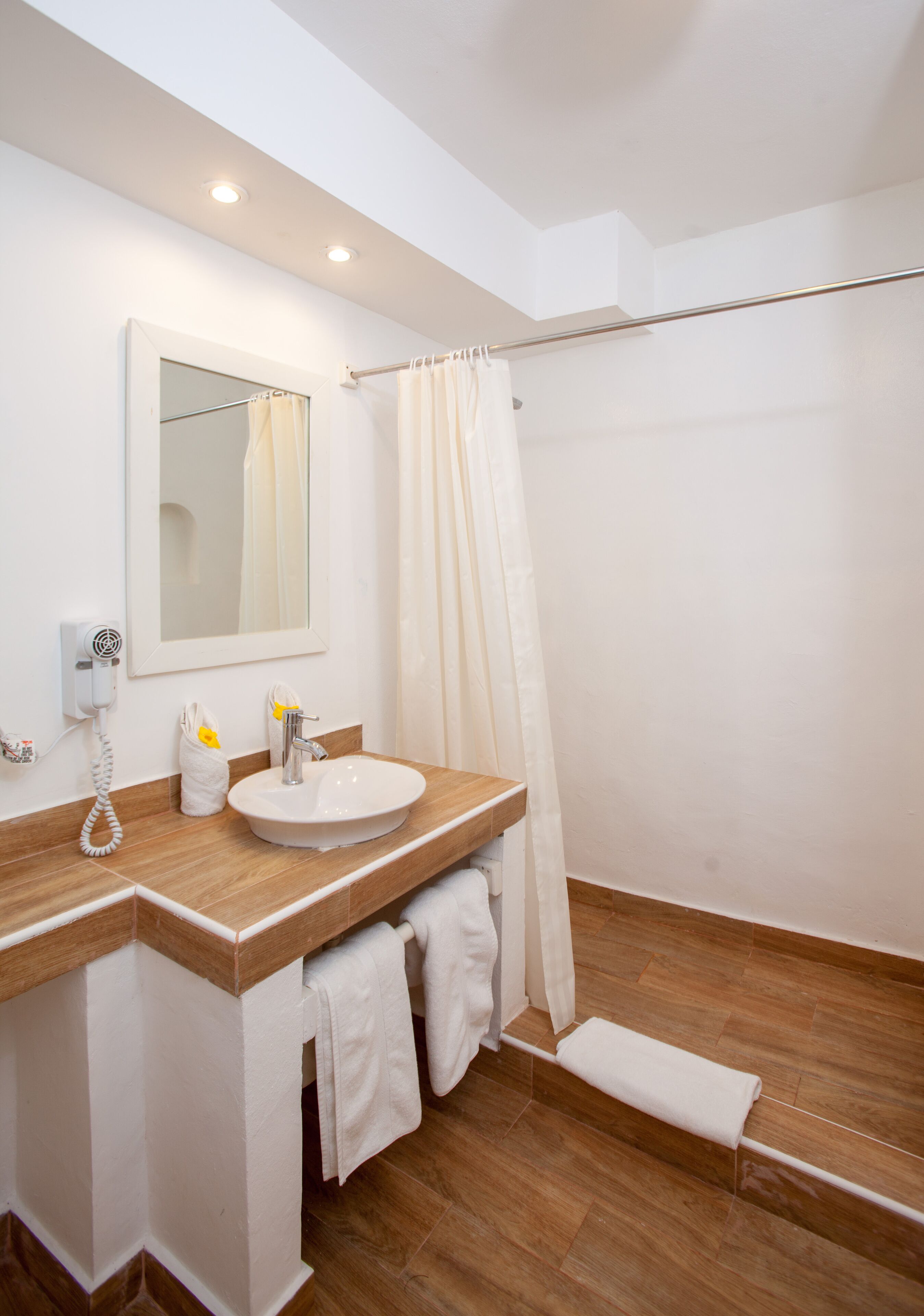 Une salle de bain moderne avec un meuble-lavabo en bois, un lavabo blanc, un miroir et un rideau de douche.