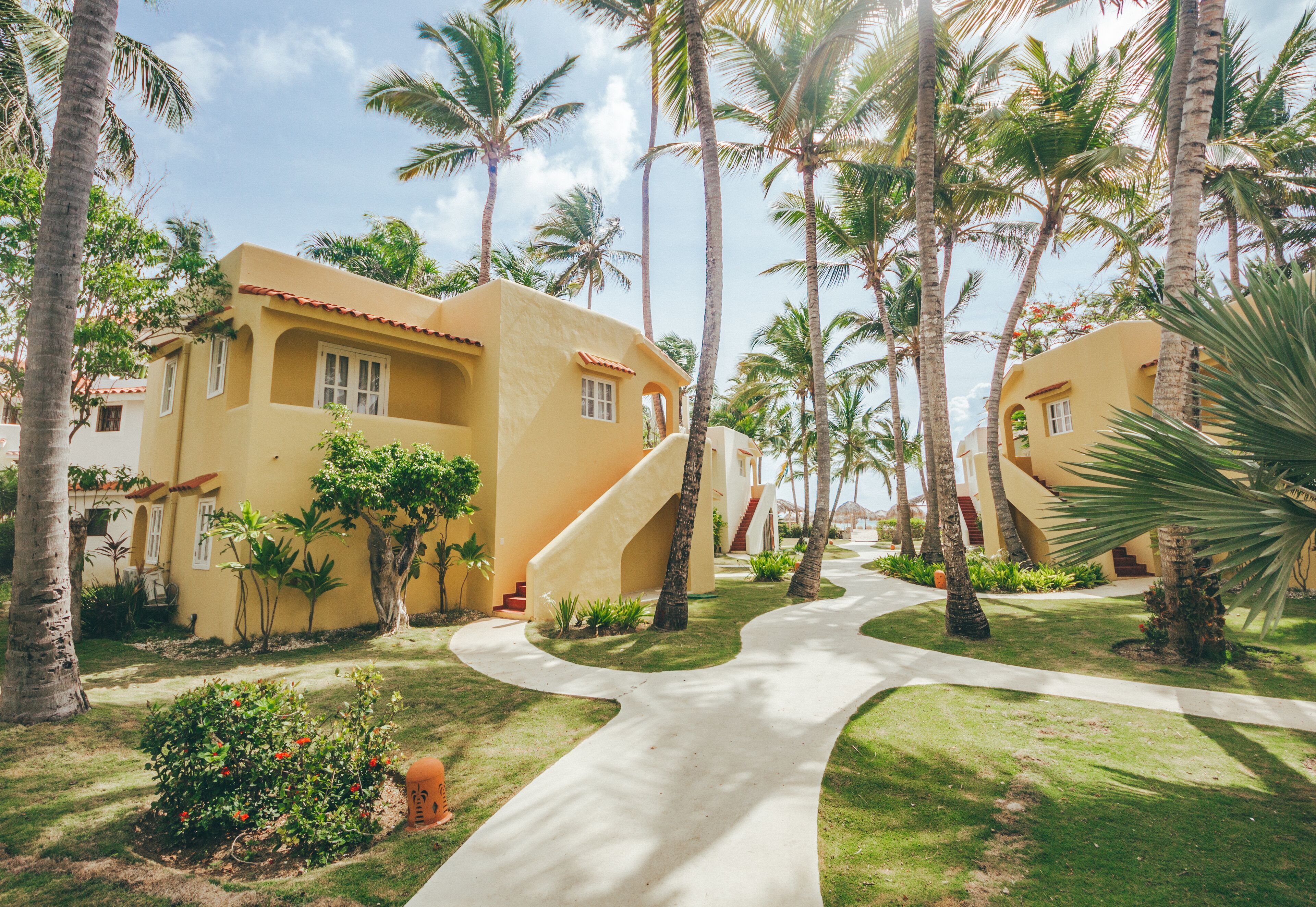 A resort with yellow buildings, palm trees, and a winding pathway.