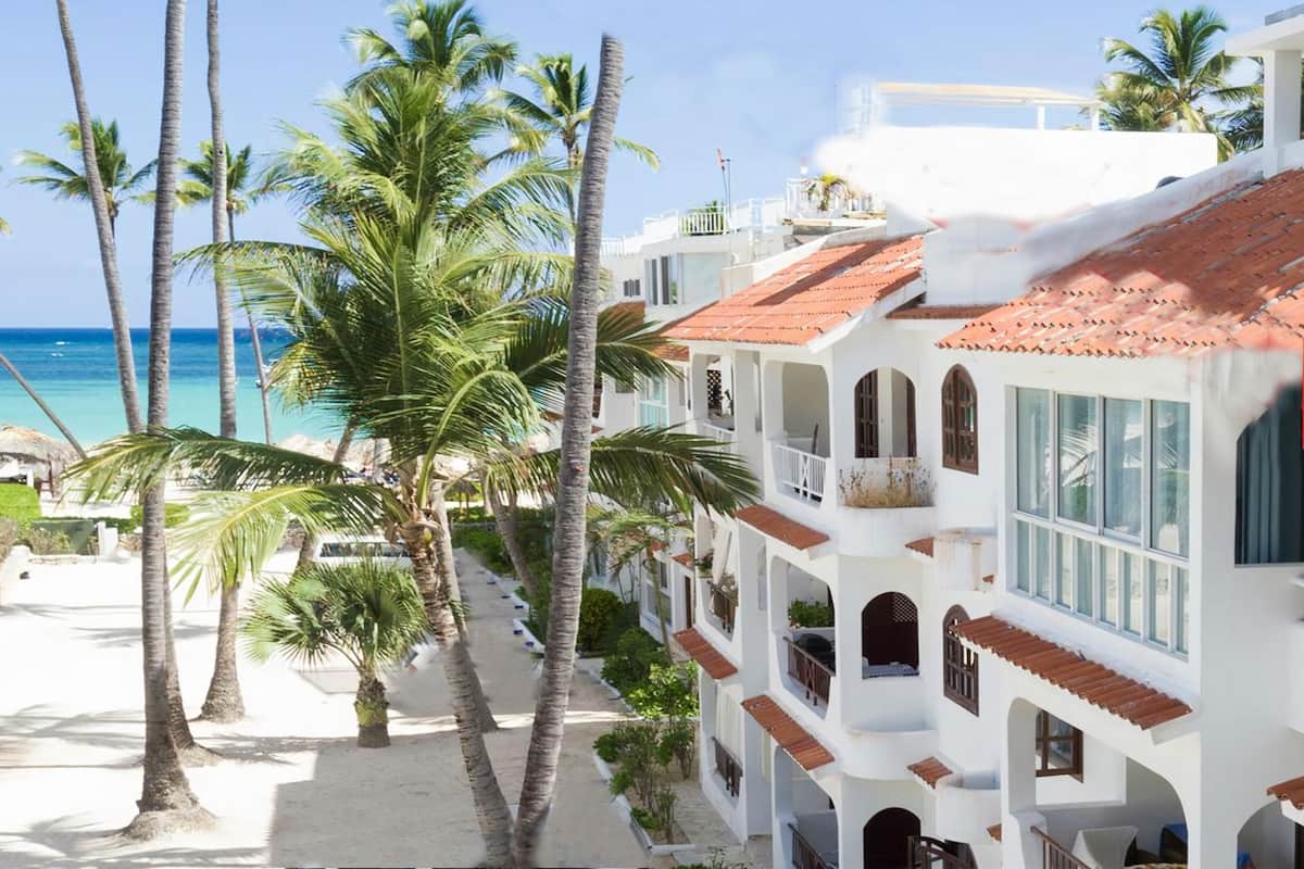 A beachfront hotel with multiple balconies and a view of the ocean.