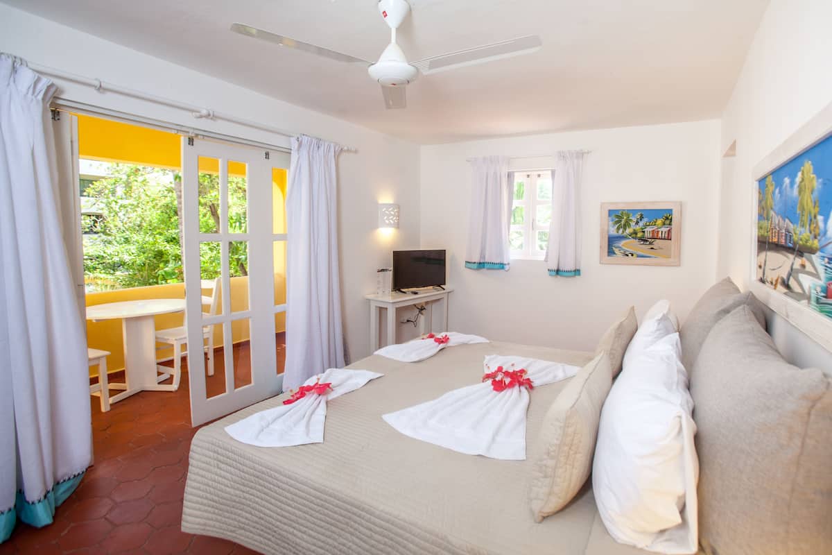 A hotel room with a bed, a TV, a desk, and a balcony.