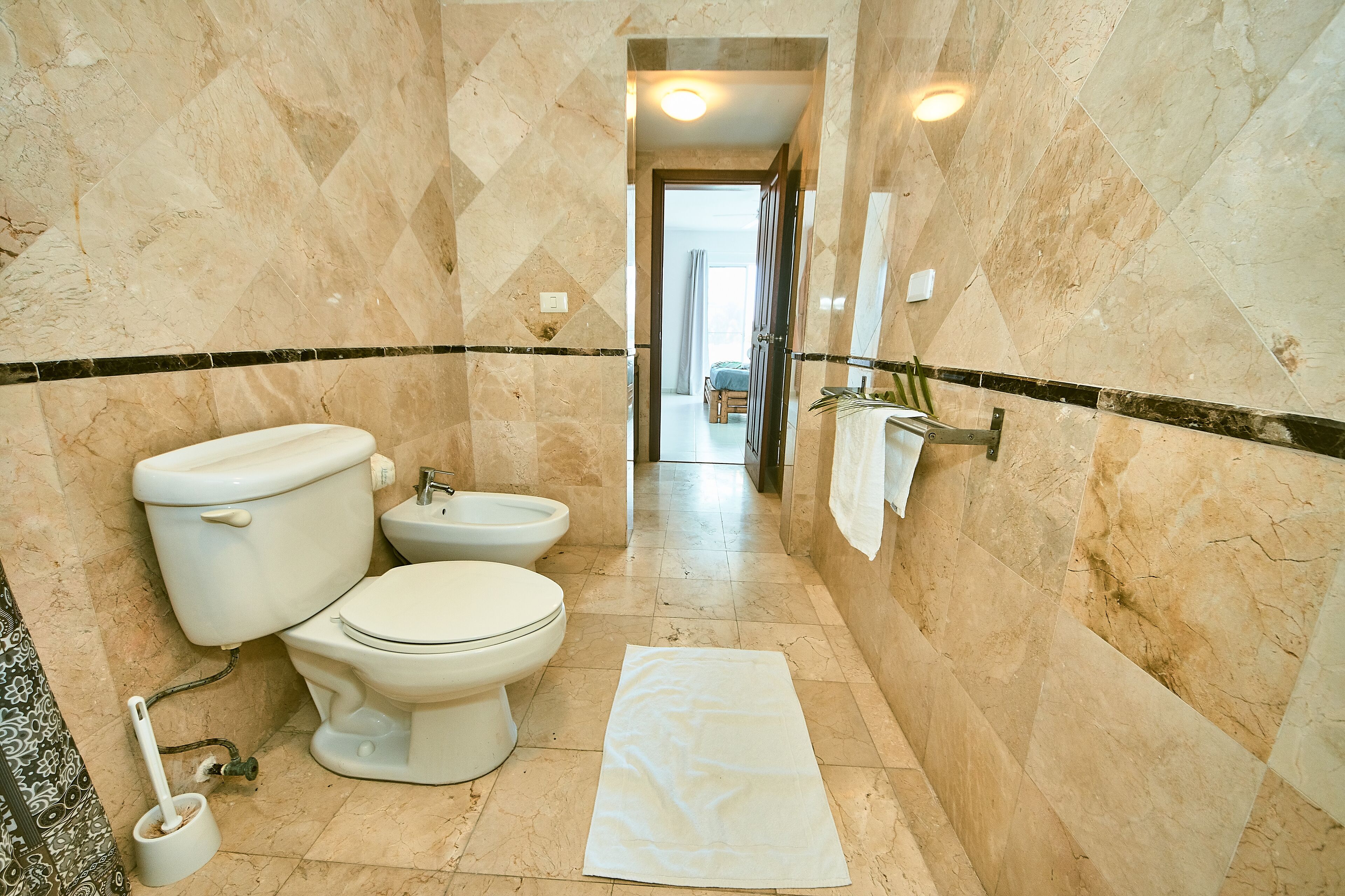 A bathroom with a toilet, bidet, and a towel on the floor.