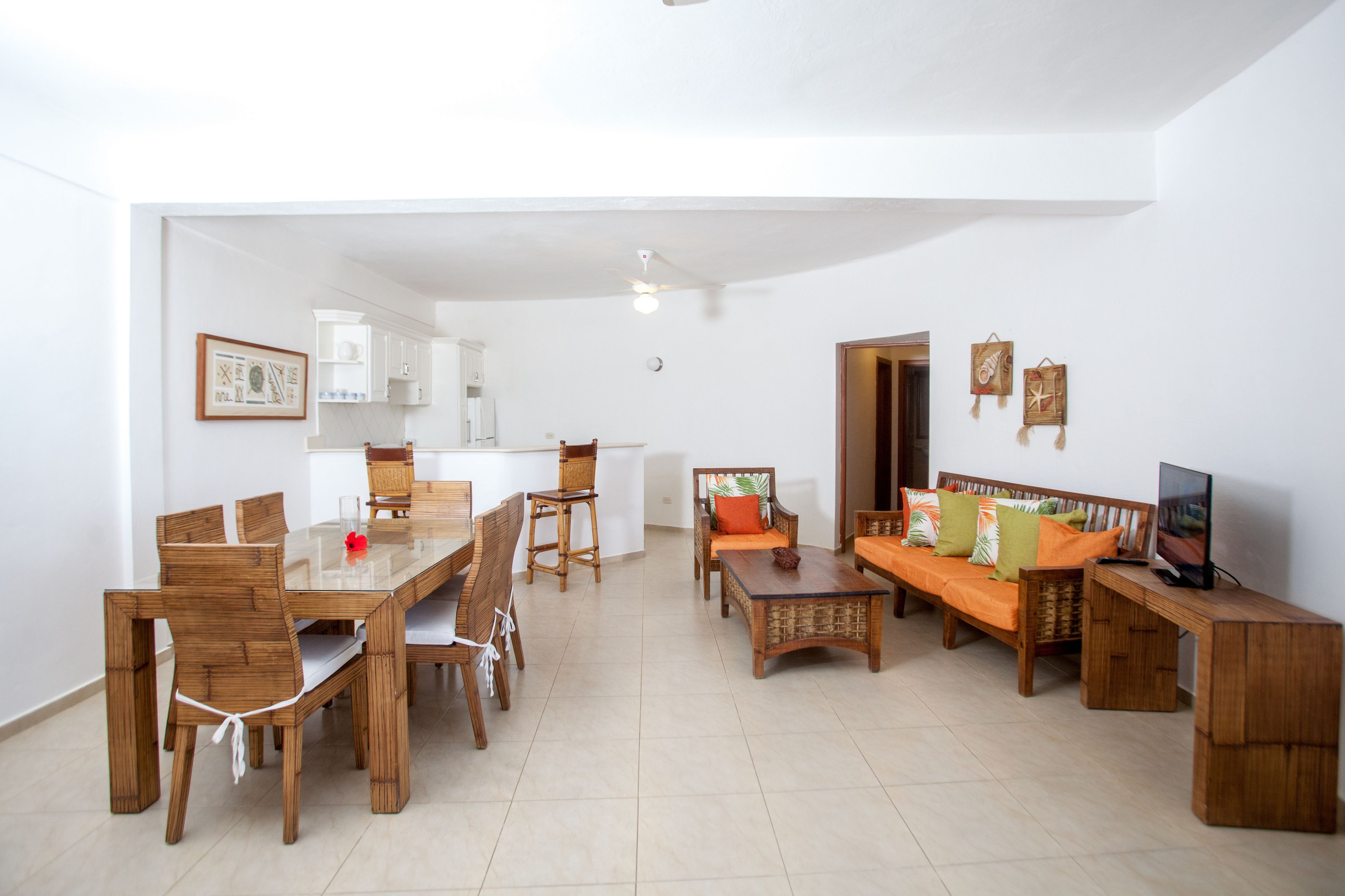 A spacious living area with a dining table, chairs, a sofa, and a TV.