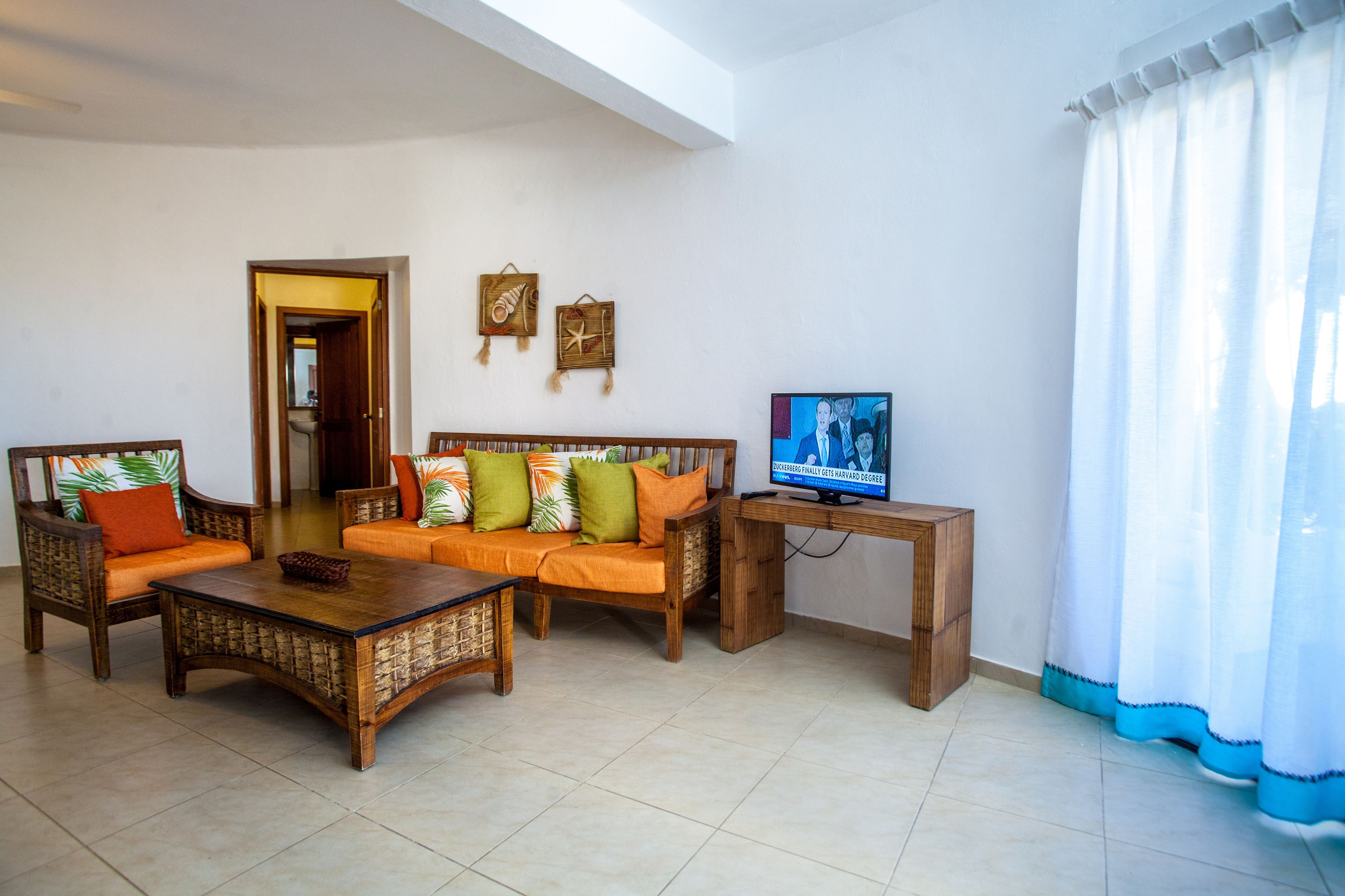 Una sala de estar con un sofá, una mesa de centro y un televisor sobre un mueble.