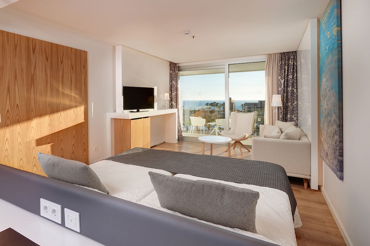 Une chambre d’hôtel moderne équipée d’un lit, d’une télévision, d’un bureau et d’un balcon avec vue.