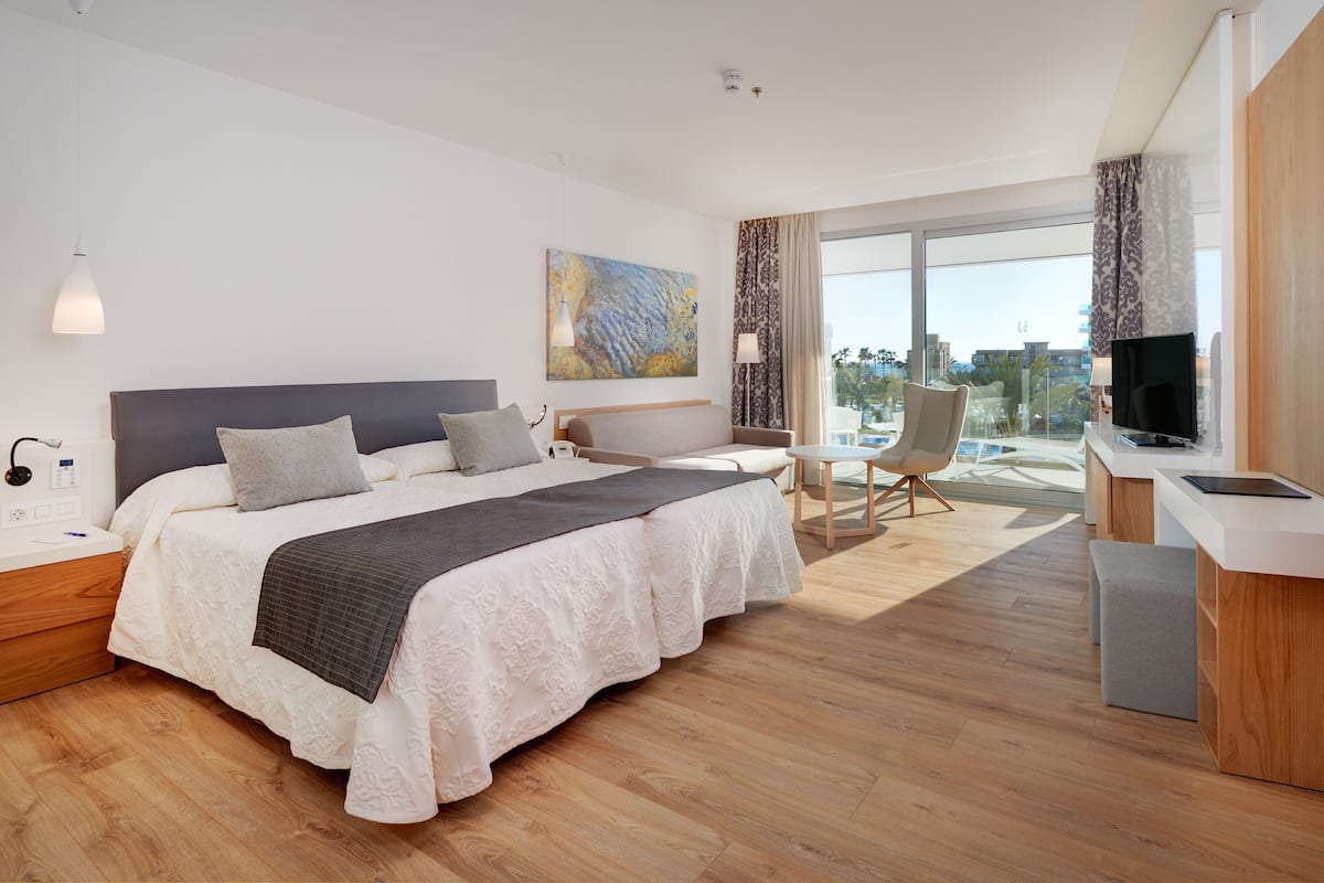 Une chambre d’hôtel moderne équipée d’un grand lit, d’un bureau, d’une chaise et d’un téléviseur.