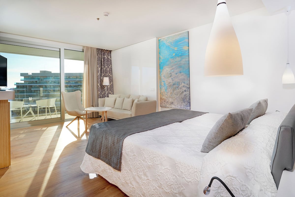 Une chambre d’hôtel moderne, dotée d’un grand lit, d’un bureau, d’une chaise, d’un canapé et d’un tableau au mur.