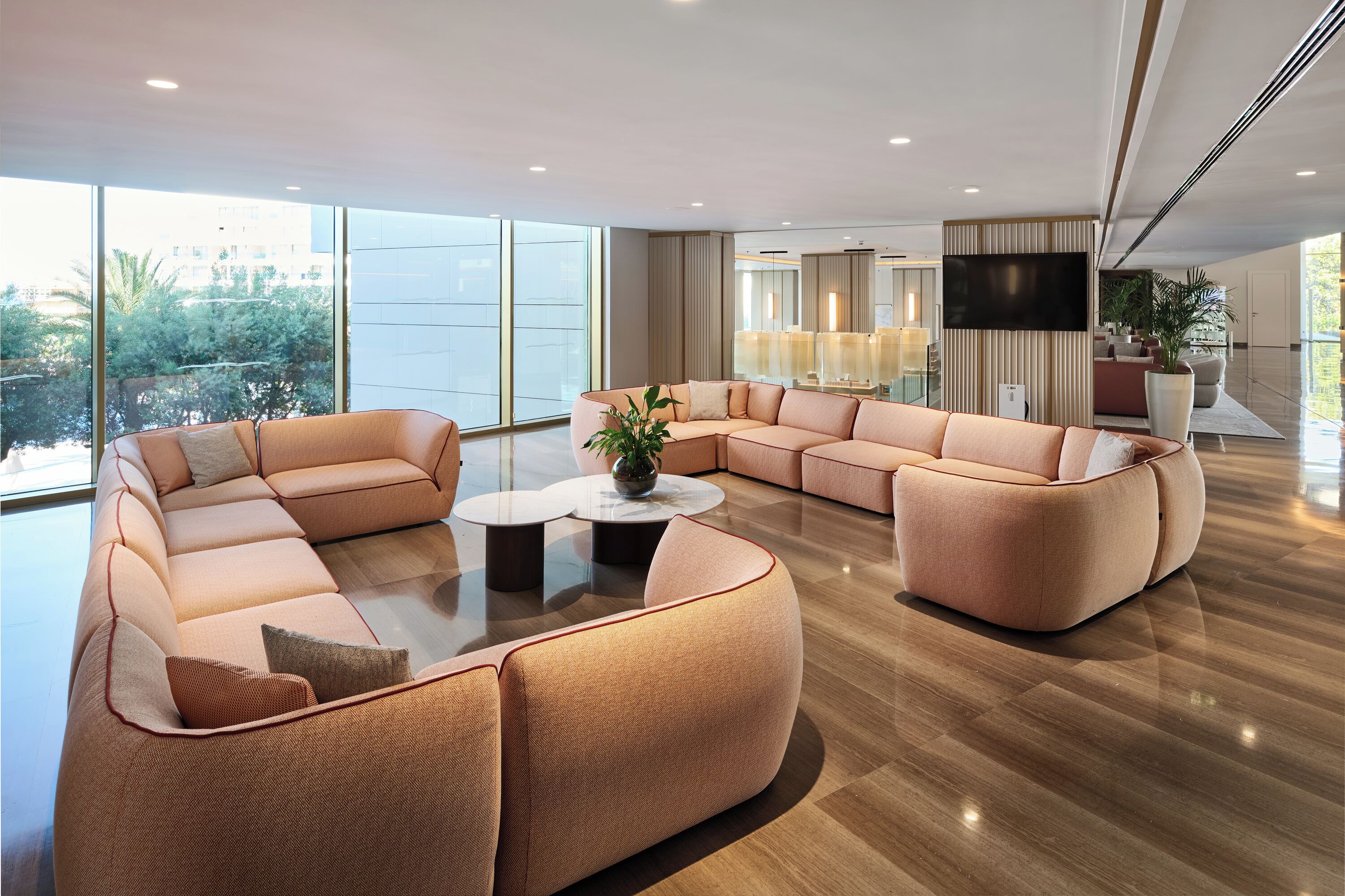 A spacious living area with a large sectional sofa, a coffee table, and a flat-screen TV mounted on the wall.
