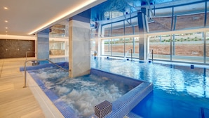 A modern indoor swimming pool with a hot tub area, large windows, and a view of the outdoors. - Hipotels Gran Playa de Palma (Palma de Mallorca)