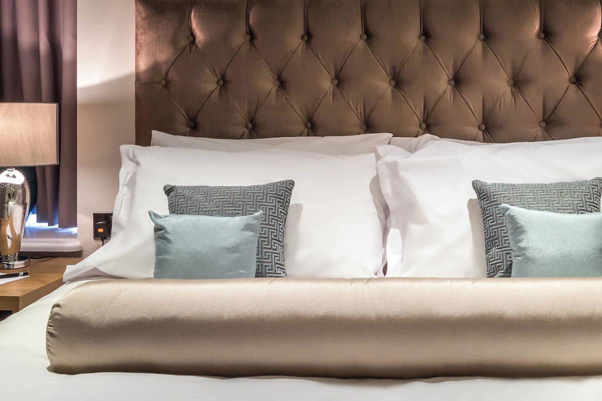 A neatly made bed with a tufted headboard, two bedside lamps, and patterned pillows.