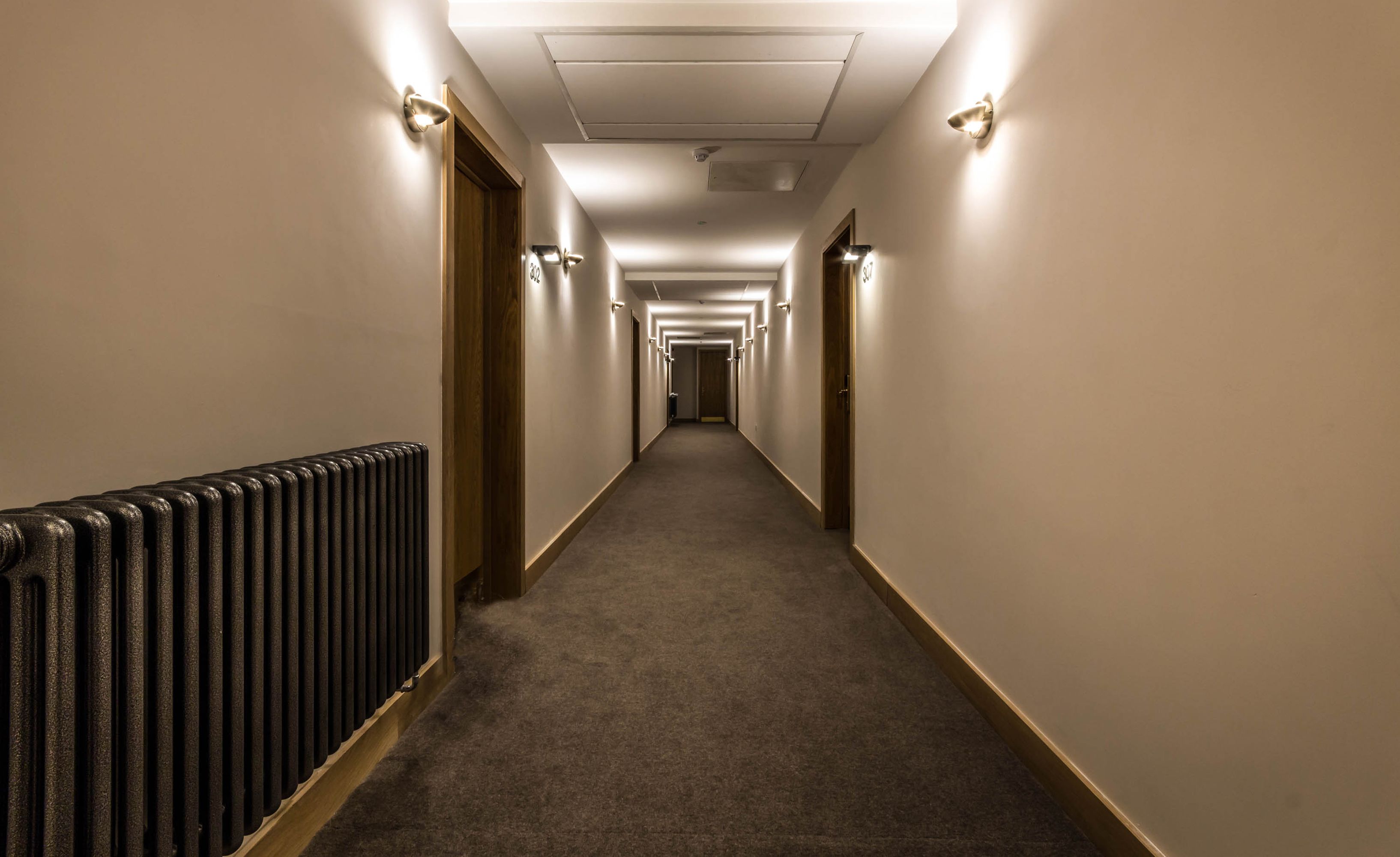 A long, narrow hallway with carpeted floors and light-colored walls.