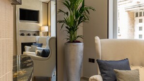 Habitación de hotel moderna con una planta grande en maceta, un televisor de pantalla plana, un sofá y una encimera de mármol.