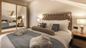 Una habitación de hotel con una cama grande, un espejo, una mesita de noche y una lámpara.