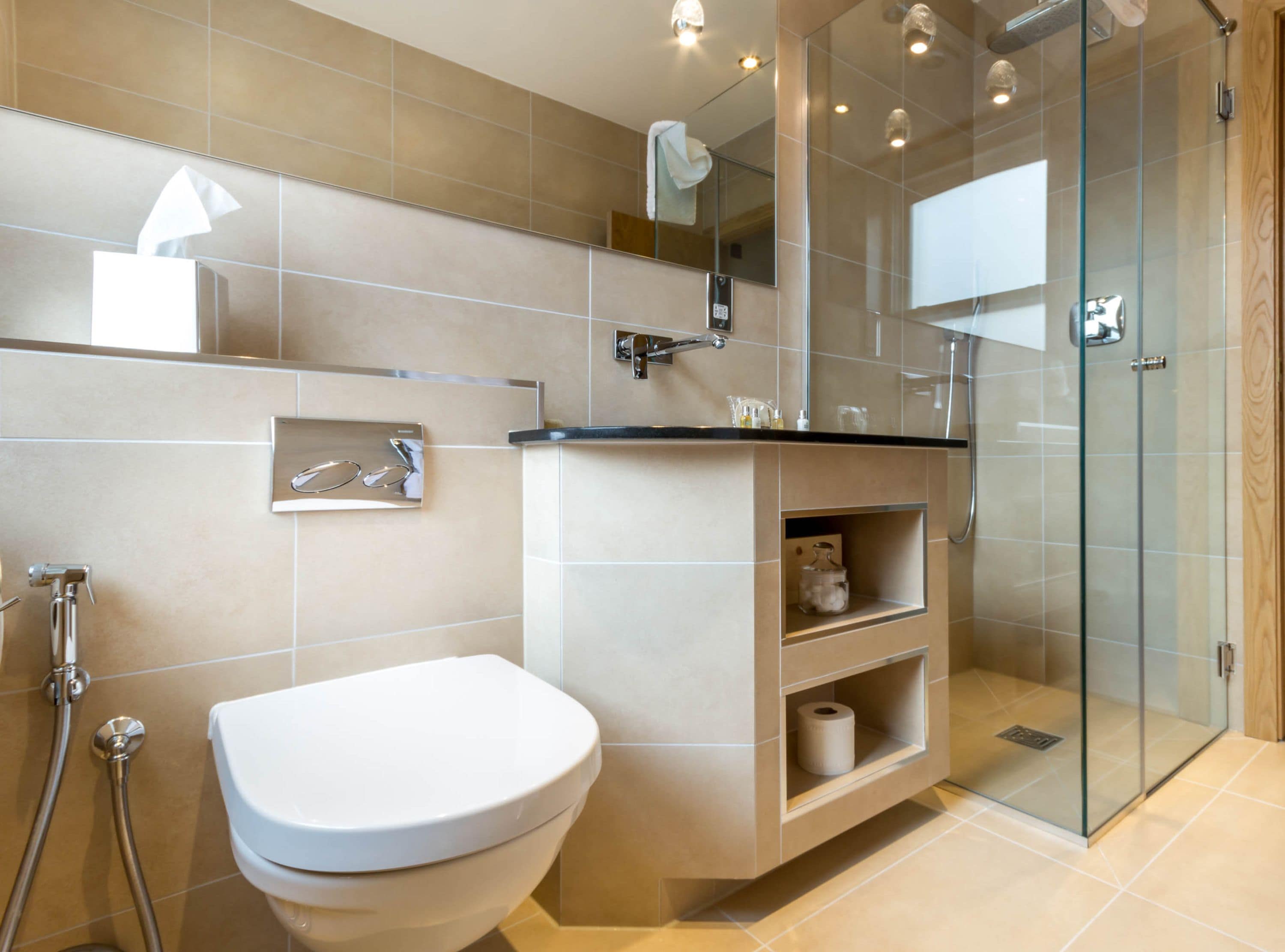 Een moderne badkamer met toilet, douche en douchecabine met glazen wanden.