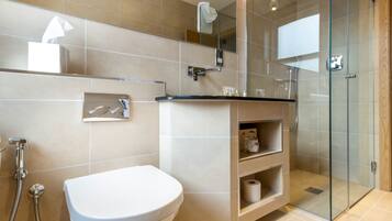 Een moderne badkamer met toilet, douche en douchecabine met glazen wanden.