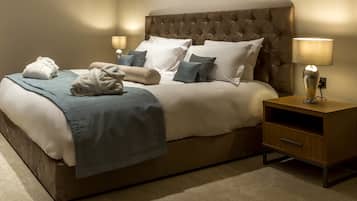 A neatly made bed with a tufted headboard, a bedside table with a lamp, and a small wooden nightstand.