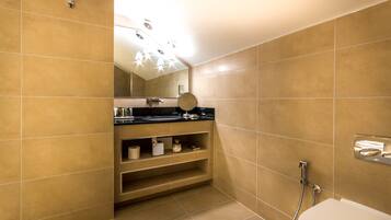 A modern bathroom with beige tiles, a black countertop, a mirror, a toilet, and a shower.