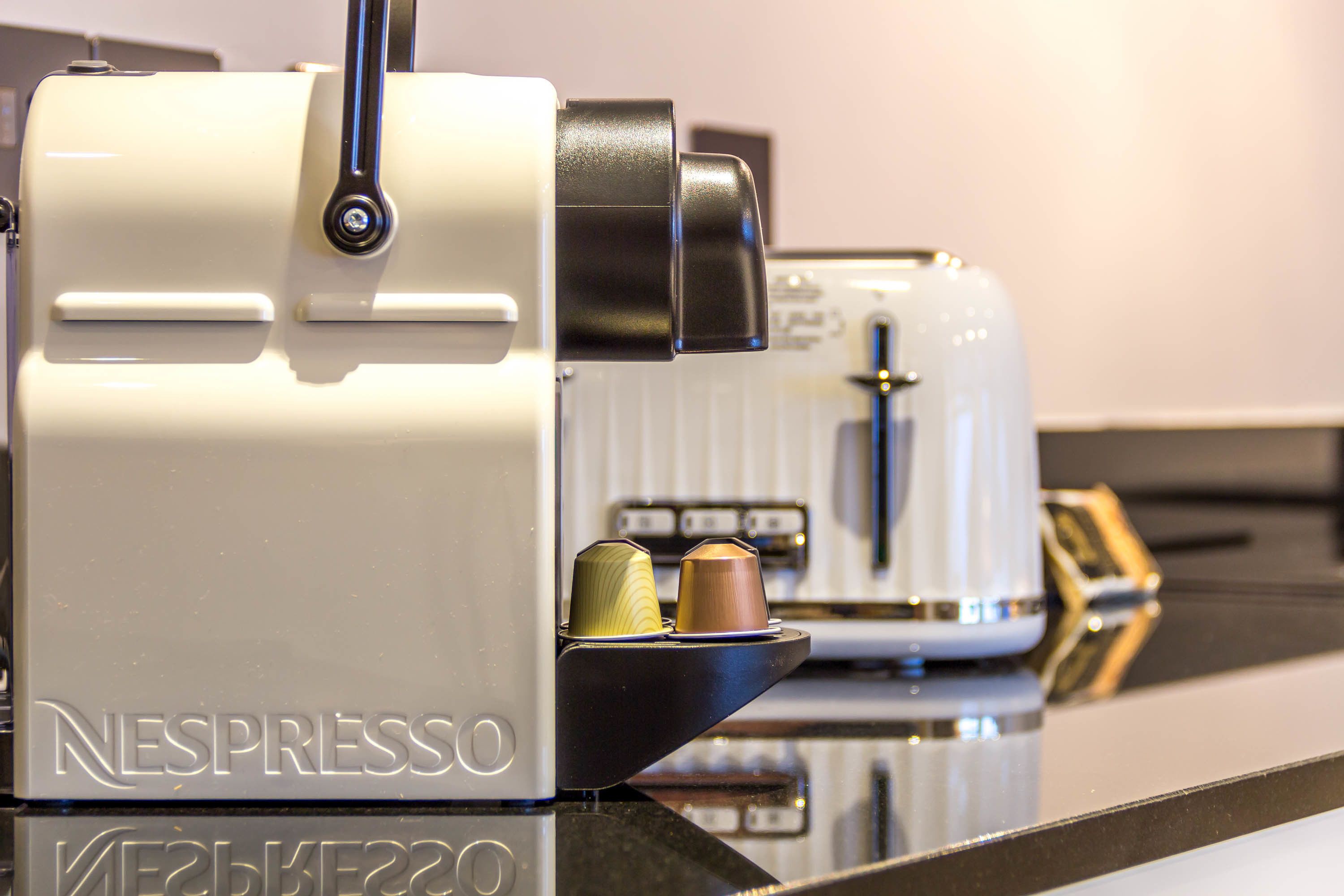 A Nespresso coffee machine with two coffee capsules on its drip tray.