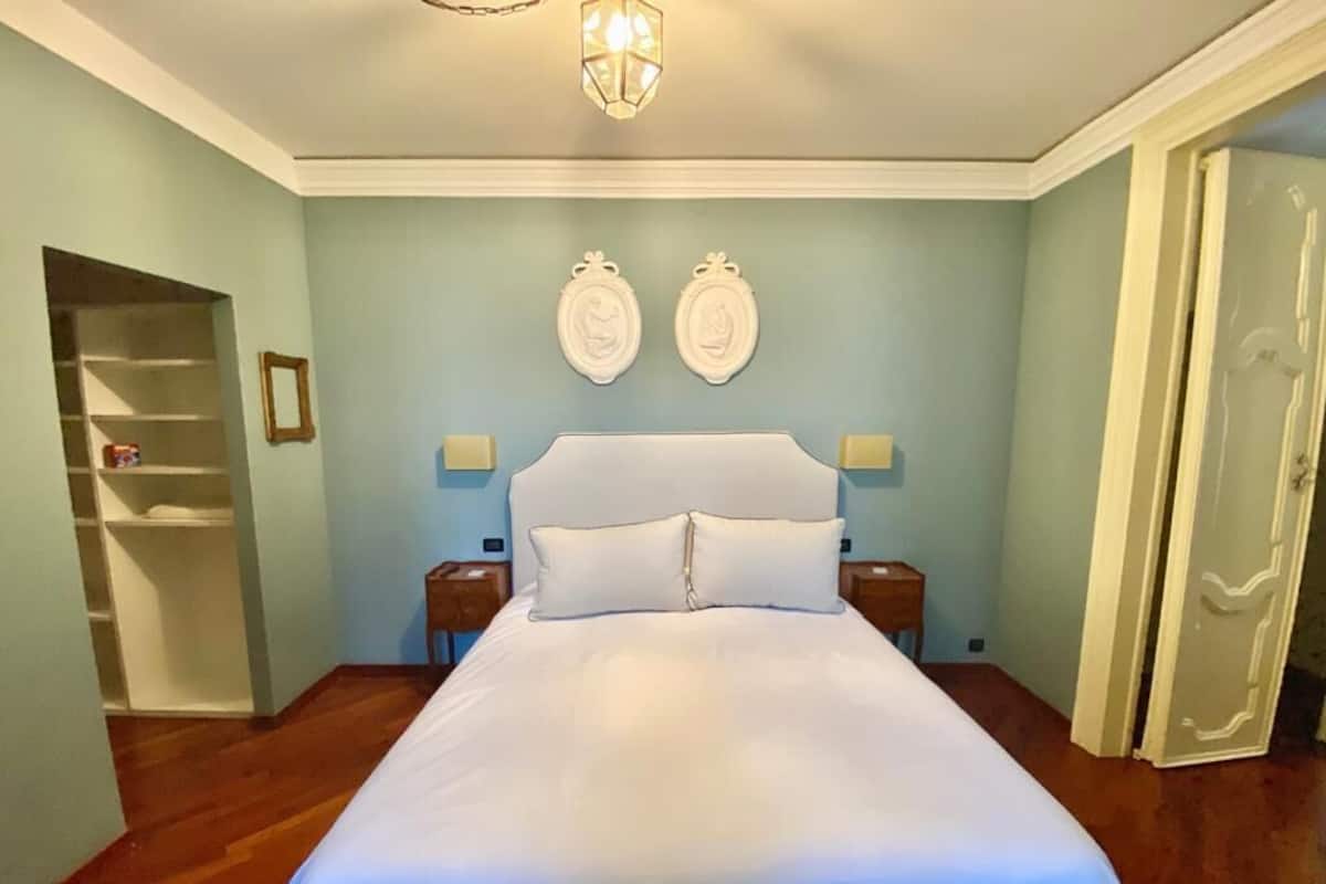Un dormitorio con una cama grande, una mesita de noche y un armario, además de una puerta.