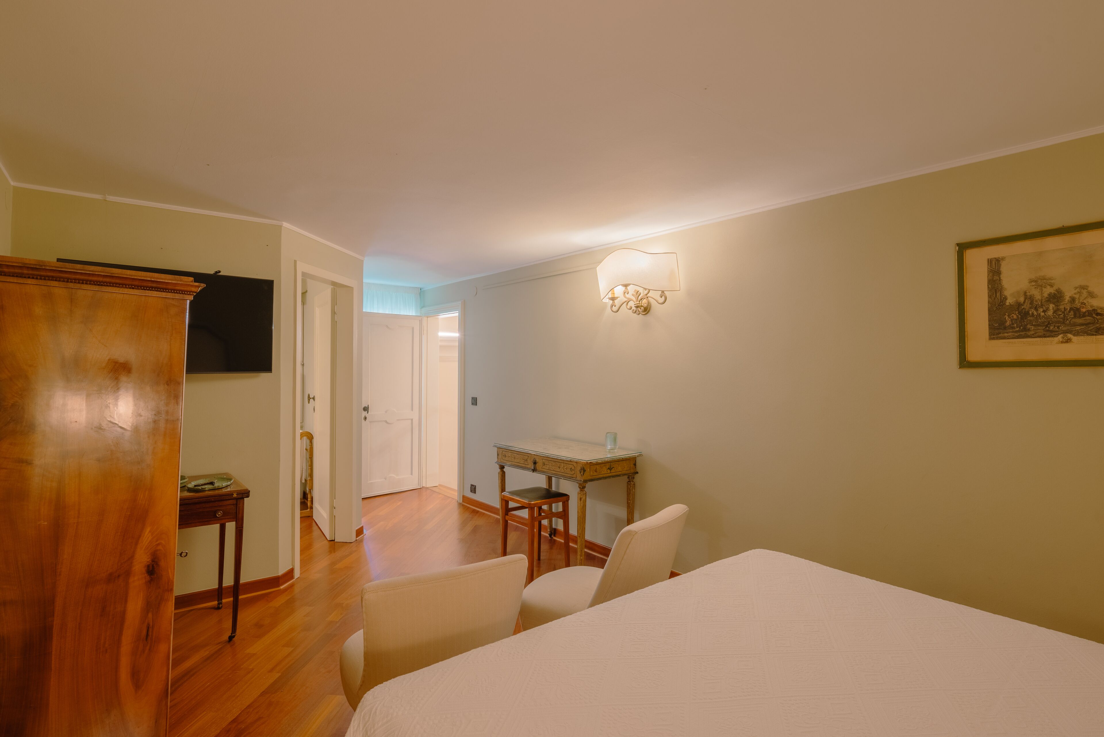 Un dormitorio con cama, dos sillones, escritorio y televisor.