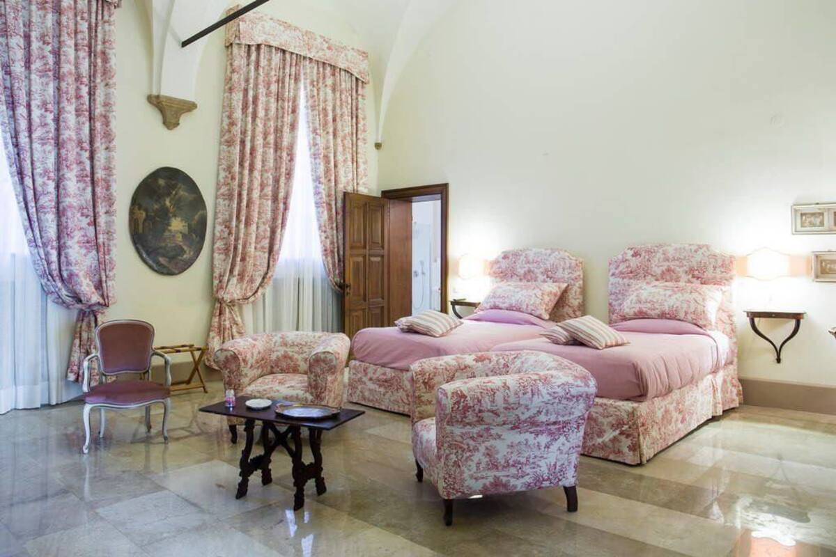 Una habitación con una cama, dos sillones, una mesita y una silla.