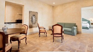 A spacious room with a wooden herringbone floor, a dining table with chairs, a green sofa, and a painting on the wall. - Palazzo Mantua Benavides Suites and Apartments (Padova)