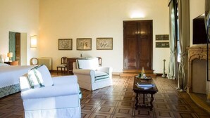 A room with a bed, a white sofa, a wooden floor, a fireplace, and framed pictures on the wall. - Palazzo Mantua Benavides Suites and Apartments (Padova)